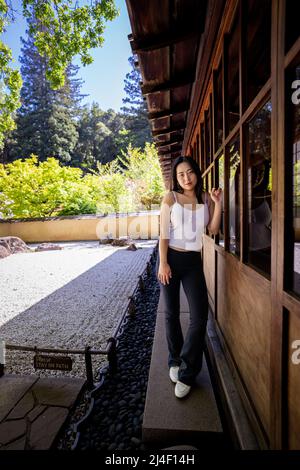 Junge Chinesin, die neben einem japanischen Steingarten steht Stockfoto