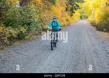 Eine Frau mittleren Alters, die mit dem Mountainbike auf dem Cascades-to-Palouse-Trail in den Eastern Cascade Mountains entlang des Yakima River, Washington, fährt. Stockfoto