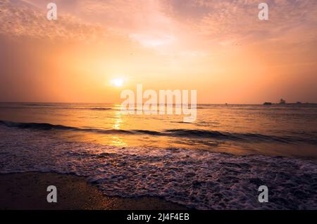 Schöne atemberaubende Sonnenuntergangslandschaft am schwarzen Meer und orangefarbenem Himmel darüber mit wunderbarer Sonne goldener Spiegelung auf ruhigen Wellen als Hintergrund. Fantastischer Summ Stockfoto