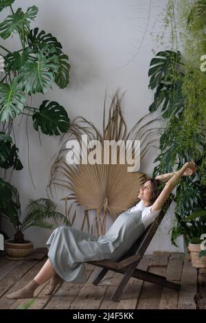 Zufriedene ruhige Frau Floristin Entspannung im Innengarten Genießen Sie geistige Balance und Wohlbefinden zu Hause Stockfoto