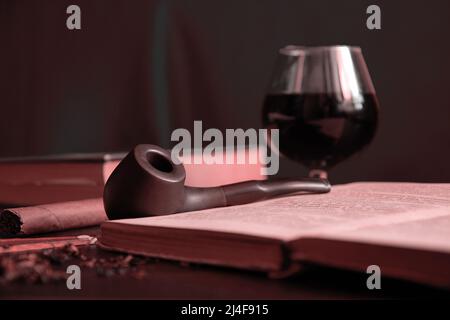 Moody Pastellbild des Lesesschrankes mit Rauchpfeife, Brandy und Büchern. Klassische Vintage-Entspannungskonzepte Stockfoto