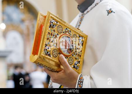 Nahaufnahme der Hände des katholischen Priesters, die die Heilige Bibel halten, Ukraine Stockfoto