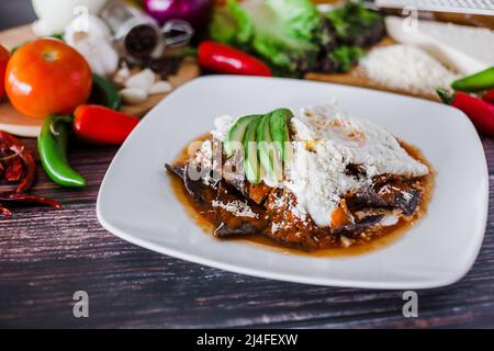 mexikanische rote Chilaquiles Essen mit Nachos, Huhn, Ei und Käse Traditionelles Frühstück in Mexiko Stockfoto