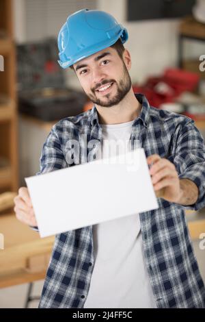 Glücklicher Bauarbeiter mit leerem weißen Brett Stockfoto