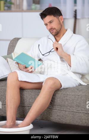 Junger Mann, der ein Buch liest und sich entspannt Stockfoto