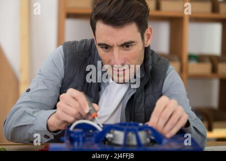 Elektriker-Werkstatt, die mit Schraubendreher an der elektrischen Einheit arbeitet Stockfoto