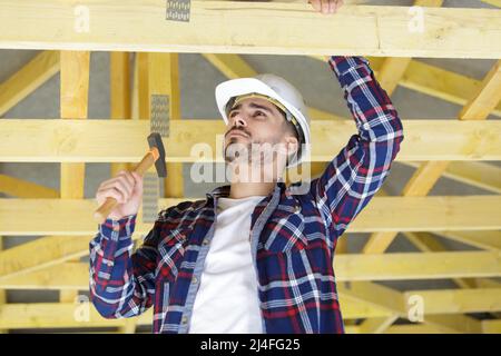 Schlauer Arbeiter mit Hammer an der Decke Stockfoto