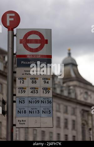 LONDON, Großbritannien - 13. APRIL 2022: Bushaltestelle des Londoner Nahverkehrs am Piccadilly Circus mit defokussiertem Gebäude im Hintergrund Stockfoto