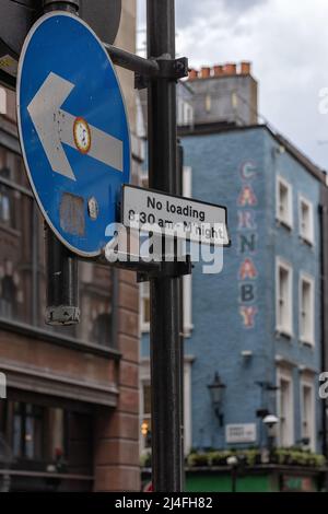 LONDON, Großbritannien - 13. APRIL 2022: Einbahniges Verkehrsschild in Soho mit unschärfem Blick auf die Carnaby Street im Hintergrund Stockfoto