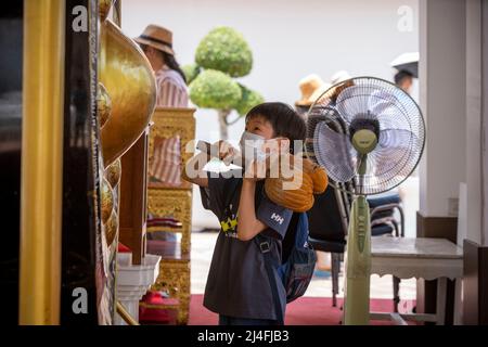 Bangkok, Bangkok, Thailand. 15. April 2022. Ein kleiner Junge trifft auf einen riesigen gong im Wat Pho Tempel in Bangkok. Thailands traditionelle Neujahrsfeier auf der Grundlage des Mondkalenders, Songkran, auch bekannt als Wasserfest, findet in der Regel jedes Jahr im April oder Mai statt. Tempel im ganzen Land veranstalteten spezielle Feste und traditionelle Aktivitäten für die mehrtägige Veranstaltung, die am 13-15. April 2022 stattfindet. (Bild: © Adryel Talamantes/ZUMA Press Wire) Stockfoto