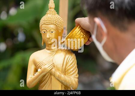 Bangkok, Thailand. 15. April 2022. Ein Mann gießt Wasser auf eine Buddha-Statue im Wat Pho in Bangkok, um einen Segen zu erhalten. Songkran, Thailands traditionelle Neujahrsfeier, die dem Mondkalender folgt, wird normalerweise von großen Straßentreffen geprägt, die sich zu massiven Wasserschlachten ausweiten. Aufgrund der Pandemie waren die Aktivitäten der letzten drei Jahre gedämpfter. Kredit: SOPA Images Limited/Alamy Live Nachrichten Stockfoto