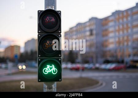 Ampel, die das Fahrrad an einem öffentlichen Ort vorbeilässt. Grünes Licht gibt Radfahrern Vorrang vor verschwommener Nahaufnahme der Stadt Stockfoto