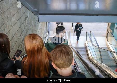 Personen, die mit einer Rolltreppe hinunterfahren Stockfoto