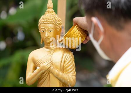 Bangkok, Thailand. 15. April 2022. Ein Mann gießt Wasser auf eine Buddha-Statue im Wat Pho in Bangkok, um einen Segen zu erhalten. Songkran, Thailands traditionelle Neujahrsfeier, die dem Mondkalender folgt, wird normalerweise von großen Straßentreffen geprägt, die sich zu massiven Wasserschlachten ausweiten. Aufgrund der Pandemie waren die Aktivitäten der letzten drei Jahre gedämpfter. (Foto von Adryel Talamantes/SOPA Images/Sipa USA) Quelle: SIPA USA/Alamy Live News Stockfoto