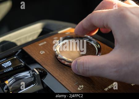 PRAG , TSCHECHISCHE REPUBLIK - MÄRZ 10 2022: Man nutzt Multimedia-Systemsteuerung im Luxuswagen BMW IX. Einstellmodus für die Hand des Fahrers in einem Fahrzeug mit stilvoller Nahansicht des Innenraums Stockfoto