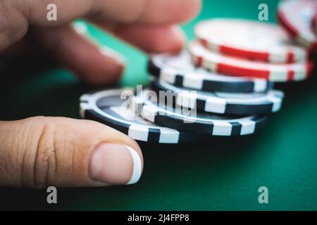 Casino-Token unter der Hand des Mädchens auf dem Pokertisch Stockfoto