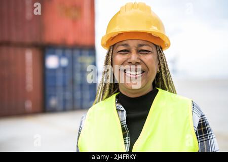 Glückliche afrikanische Frau, die im logistischen Terminal der Containerfracht arbeitet Stockfoto