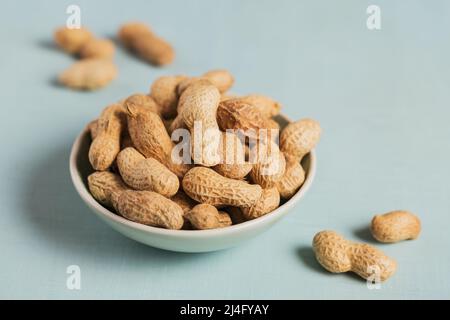 Haufen Erdnüsse in einer Schüssel auf hellblauem Hintergrund Stockfoto