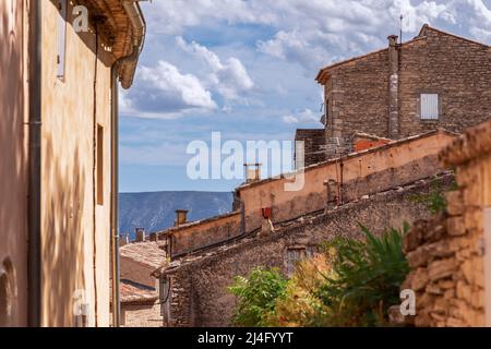 Steinmauern von Häusern in der kleinen mittelalterlichen Stadt Gordes im Südwesten der Provence mit Schornsteinen und gefliesten Dächern. Vaucluse, Provence, Alpes, Cote d'Azur Stockfoto