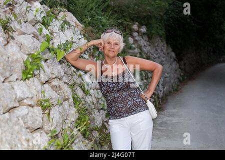 Ältere Frau, die sich am Meer entspannt Stockfoto