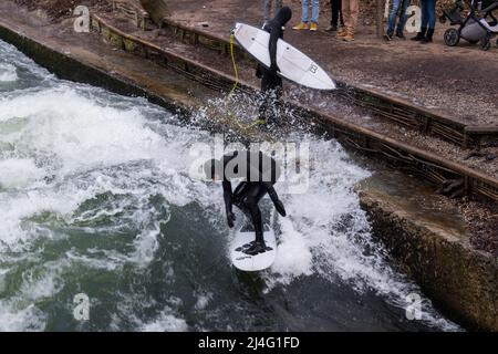 München, Deutschland - 20. Dezember 2021: Surfer in der Stadt München ist berühmt für seine Surfer in der Stadt Eisbach. Stockfoto