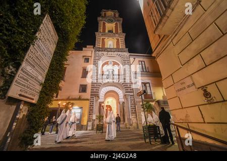 Sorrento, Italien. 14. April 2022. Kapuzen-Büßer der Arciconfraternita di Santa Monica tragen Kreuze und Fackeln, während sie an der Karfreitagsprozession entlang der Straßen von Sorrento Süditalien teilnehmen. Christliche Gläubige auf der ganzen Welt feiern die Osterwoche zur Feier der Kreuzigung und Auferstehung Jesu Christi. Sorrento am 15. April 2022 in Neapel, Italien. Quelle: Franco Romano/Alamy Live News Stockfoto