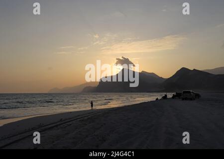 Sonnenuntergang über den Küstenbergen vom Strand im Süden Omans Dezember Stockfoto