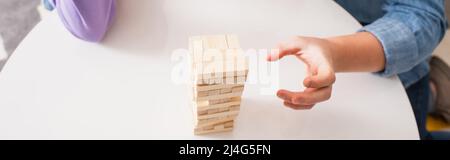 Beschnittene Ansicht von Teenager spielen Holzklötze Spiel auf Couchtisch zu Hause, Banner Stockfoto