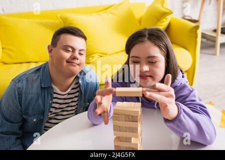 Positive Jugendliche mit Down-Syndrom spielen Holzklötze Spiel zu Hause Stockfoto