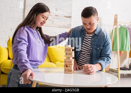 Positive Freunde mit Down-Syndrom spielen Holzklötze Spiel auf Couchtisch zu Hause Stockfoto