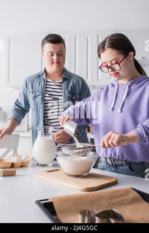 Teenager mit Down-Syndrom Kochen in der Nähe von Essen und Freund in der Küche Stockfoto