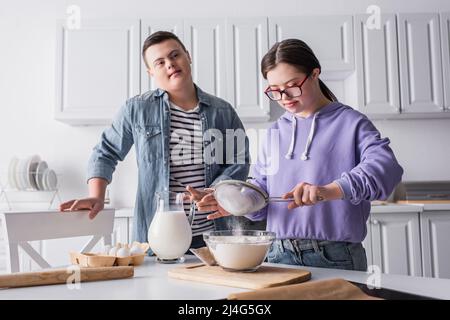 Teen Mädchen mit Down-Syndrom Kochen in der Nähe Freund in der Küche Stockfoto