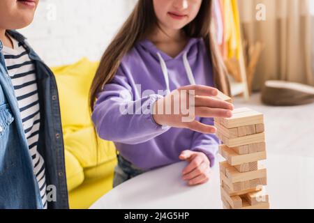 Beschnittene Ansicht von verschwommenen Teenagern mit Down-Syndrom, die zu Hause Holzklötze spielen Stockfoto