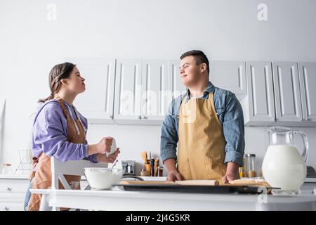 Positives Paar mit Down-Syndrom Kochen in der Nähe von Lebensmitteln in der Küche Stockfoto