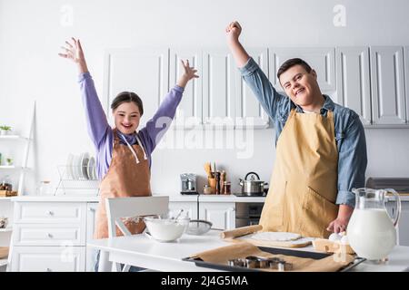 Aufgeregt Freunde mit Down-Syndrom stehen in der Nähe von Lebensmitteln in der Küche Stockfoto