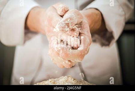Kaukasischer Küchenchef bereitet Bio-Teig vor Mischen von Mehl, Wasser und Hefe. Nahaufnahme Der Hände. Stockfoto