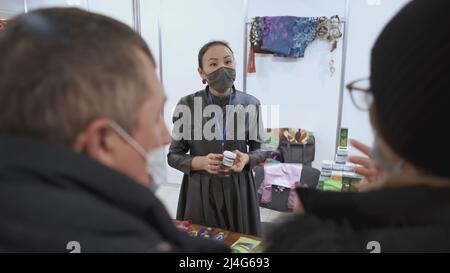 JEKATERINBURG, RUSSLAND - 25. FEBRUAR 2022: Die Verkäuferin zeigt Kunden ihre Produkte an. KUNST. Ein taubstummes Mädchen spricht in Gebärdensprache darüber Stockfoto