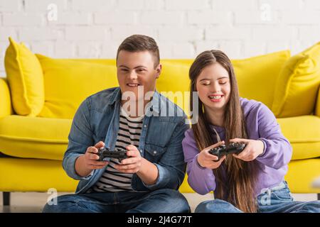 KIEW, UKRAINE - 21. JANUAR 2022: Positive Jugendliche mit Down-Syndrom spielen zu Hause Videospiele Stockfoto