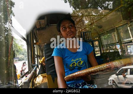 Kalkutta, Westbengalen, Indien. 15. April 2022. Kalpana Mondal, 19 Jahre alt, fährt am 15. April 2022 in Kalkata, Indien, einen privaten Linienbus. Sie übernahm die Verantwortung, nachdem ihr Vater vor vier Jahren beim Fahren des Busses einen Unfall hatte. Jetzt hilft ihr Vater ihr als Chefin des Busses und sie bleibt bei ihr, während sie den Bus fährt, um ihre Familie finanziell stabil zu machen. (Bild: © Indranil Aditya/ZUMA Press Wire) Stockfoto