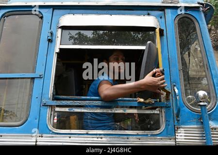 Kalkutta, Westbengalen, Indien. 15. April 2022. Kalpana Mondal, 19 Jahre alt, fährt am 15. April 2022 in Kalkata, Indien, einen privaten Linienbus. Sie übernahm die Verantwortung, nachdem ihr Vater vor vier Jahren beim Fahren des Busses einen Unfall hatte. Jetzt hilft ihr Vater ihr als Chefin des Busses und sie bleibt bei ihr, während sie den Bus fährt, um ihre Familie finanziell stabil zu machen. (Bild: © Indranil Aditya/ZUMA Press Wire) Stockfoto