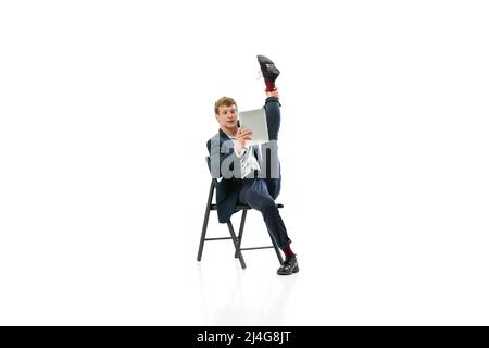 Porträt eines jungen, gutaussehenden Mannes, Büroangestellter, der auf einem Bürostuhl sitzt und Tablet auf weißem Hintergrund verwendet Stockfoto