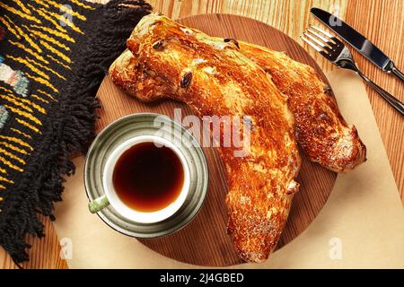 Traditionelles, frisch gebackenes, süßes georgisches Brot, Nazuki mit Rosinen, serviert mit einer Tasse Tee auf einem hölzernen Servierbrett. Authentisches nationales Bäckerkonzept Stockfoto