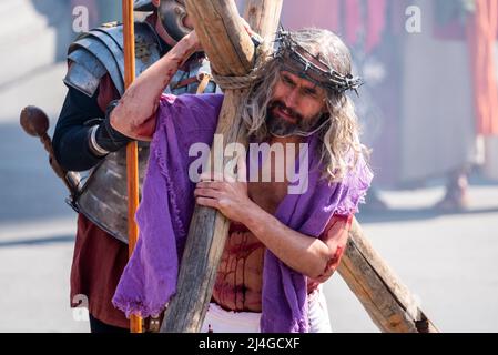 Trafalgar Square, London, Großbritannien. 15. April 2022. ‘Karfreitag an Ostern präsentierte die Besetzung von Wintershall die ‘Passion Jesu’, ein Stück, das die biblische Geschichte Christi durch die „Wunder“, das letzte Abendmahl, Und die Kreuzigung durch die Römer, bevor sie wieder auferstehen, und die Auferstehung, die alle den Trafalgar Square als Bühne für die kostenlose öffentliche Veranstaltung nutzen. Christus wird vom Schauspieler James Burke-Dunsmore dargestellt, der die Rolle seit vielen Jahren spielt. Jesus trägt das Kreuz, blutig, mit Dornenkrone Stockfoto