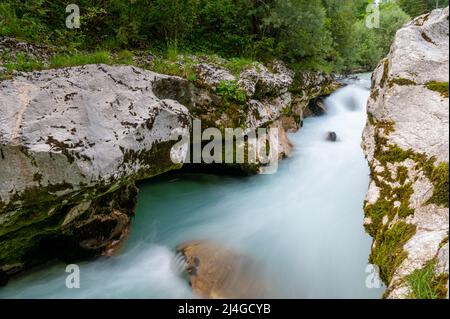 Schönes unscharfes Bild des Flusses Soca, der durch die felsige Sommernatur fließt. Stockfoto