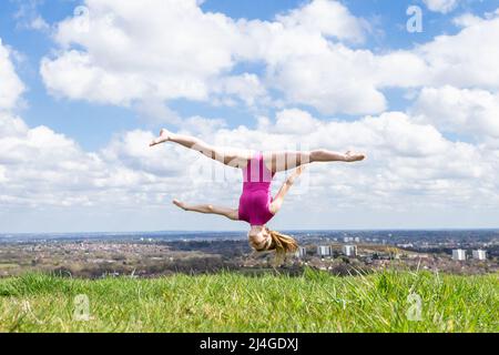 Birmingham, Großbritannien. 15. April 2022. Die 17-jährige Tanzstudentin Amelia Hubbard aus Halesowen, West Midlands, fährt in den Park im Süden von Birmingham, um einige Frühlingsbewegungen zu machen, da die Temperaturen in Großbritannien am Karfreitag ansteigen. Kredit: Peter Lopeman/Alamy Live Nachrichten Stockfoto