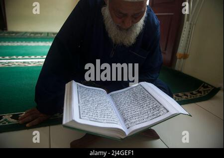 Ein behinderter Flüchtling aus Burma, Firazul Haq, 67, wird gesehen, liest den heiligen Koran während der Teilnahme muslimischer Asylsuchender Kinder an der Flash-Internat-Ausbildung während des heiligen Monats Ramadan in einem vorübergehenden Immigrantenheim in Medan, Provinz Nord-Sumatra, Indonesien am 15. April 2022. Foto von Aditya Sutanta/ABACAPRESS.COM Stockfoto