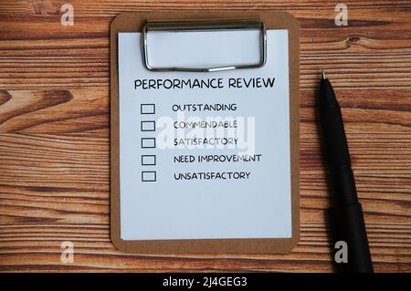 Draufsicht der Leistungsbeurteilung Checkliste auf Clipboard mit Stift und Holzabdeckung Hintergrund. Konzept der Leistungsbeurteilung Stockfoto