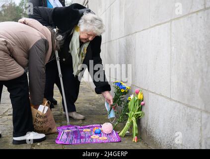 Bergen, Deutschland. 15. April 2022. Anastasia Gulej (r) aus Kiew besucht das KZ-Denkmal Berge-Belsen und legt Blumen. Der Überlebende der Lager Auschwitz, Buchenwald und Bergen-Belsen musste vor dem Krieg in fortgeschrittenem Alter aus der Ukraine nach Deutschland fliehen. Quelle: Julian Stratenschulte/dpa/Alamy Live News Stockfoto