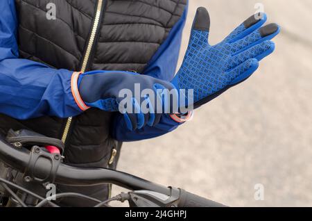 Nahaufnahme eines Radfahrers, der Sporthandschuhe anlegt. Warme Sporthandschuhe an der Hand einer Frau Stockfoto