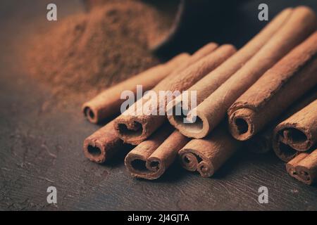 Aromatische Zimtschnecken und Pile von bestreut gemahlenem Zimt auf dem Hintergrund. Selektiver Fokus. Stockfoto